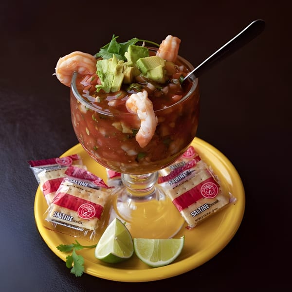 Camila's Mexican Restaurant's shrimp cocktail with avocado, cilantro, and lime on a yellow plate.